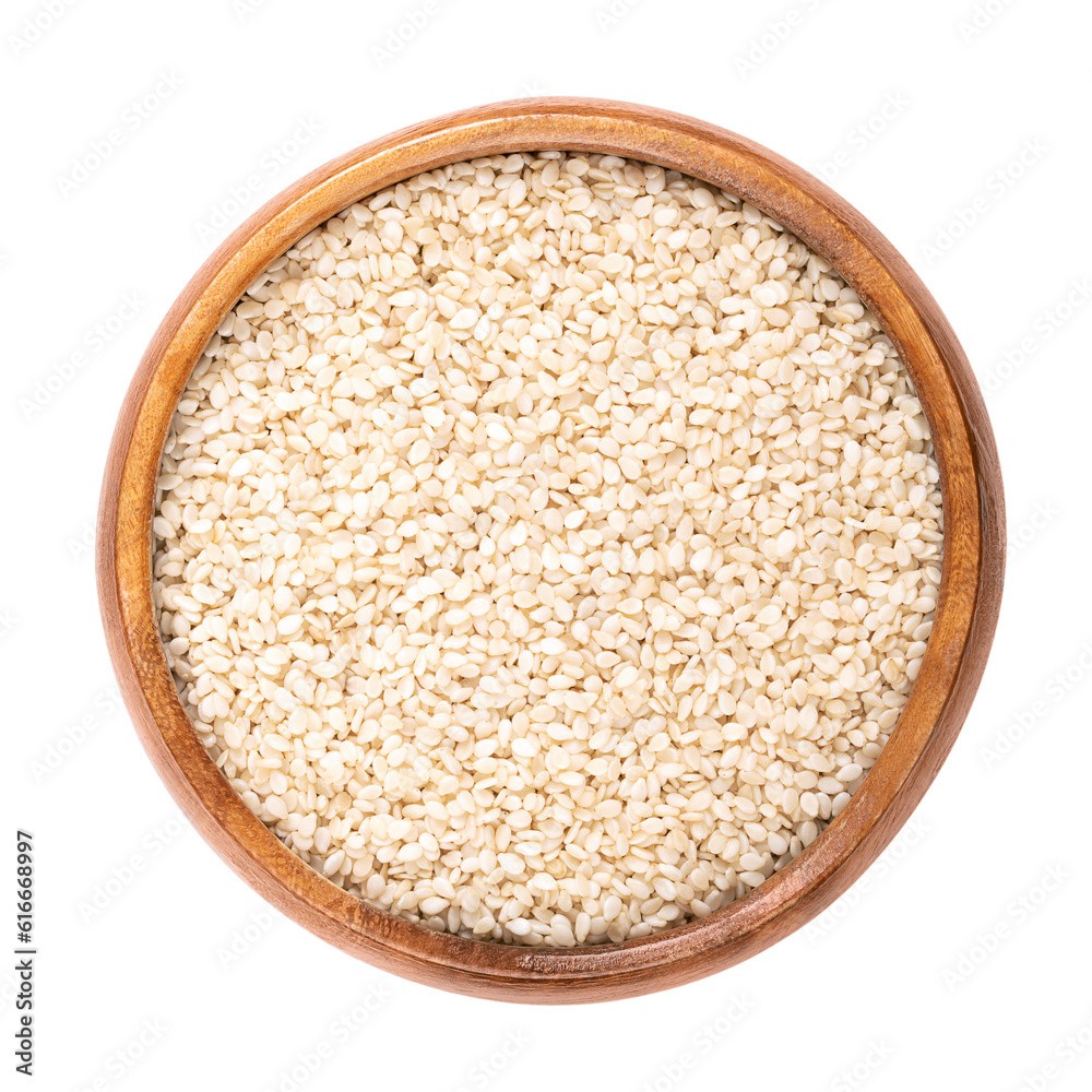 Hulled sesame seeds, white sesame in a wooden bowl. Sesamum indicum, also called benne, with rich and nutty flavor, and with one of the highest oil content of any seed. Isolated, macro food photo. Hulled sesame seeds, white sesame in a wooden bowl. Sesamum indicum, also called benne, with rich and nutty flavor, and with one of the highest oil content of any seed. Isolated, macro food photo.