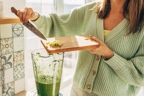 Girl hands prepare a green smoothie, puts fresh spinach leaves in a blender. Healthy eating concept. Vegetarianism, vegan food, fitness food, detox, youth preservation.
