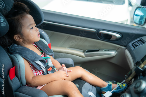 Happy preschool girl sitting on carseat while car travel trip photo