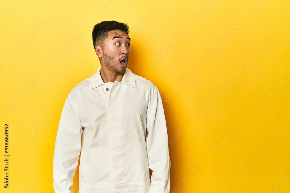 Asian man in crisp white shirt on yellow studio being shocked because of something she has seen. Asian man in crisp white shirt on yellow studio being shocked because of something she has seen.