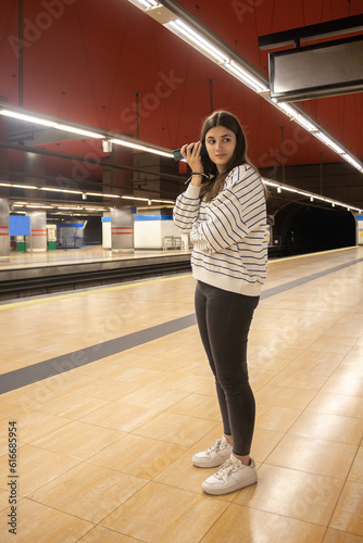teenage girl in subway or subway station listening to a cell phone message with copy space