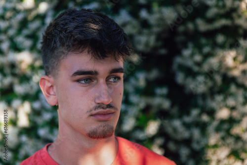 guapo joven pensativo de ojos azules, con la mirada perdida y una increíble luz sobre un fondo verdoso y difuminado.
