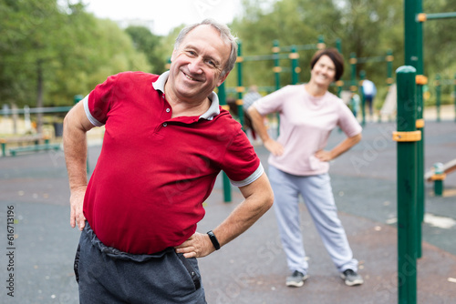 Aged man and woman practicing gymnastics in open-air sports area