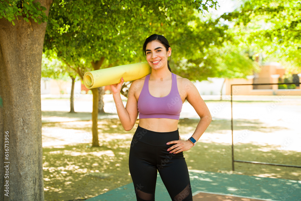 Active young woman with a yoga mat outdoors smiling Active young woman with a yoga mat outdoors smiling