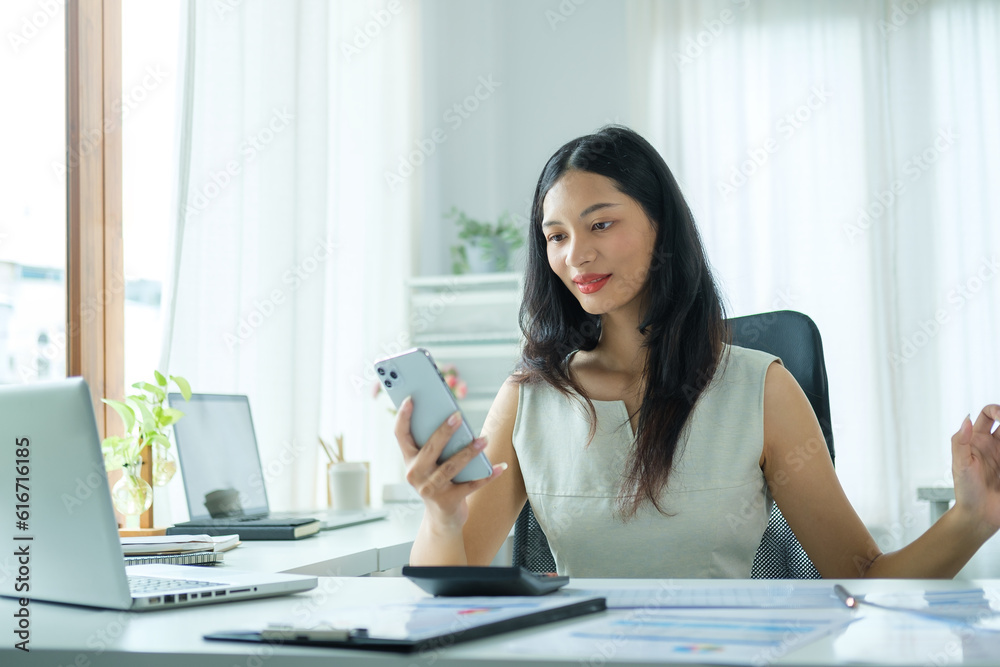 Beautiful asian businesswoman sitting at her workplace and using smart phone. Beautiful asian businesswoman sitting at her workplace and using smart phone.