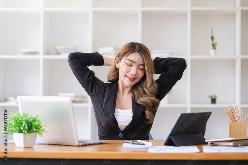 Satisfied asian young woman relaxing at her workplace and looking through the window at office. Satisfied asian young woman relaxing at her workplace and looking through the window at office.