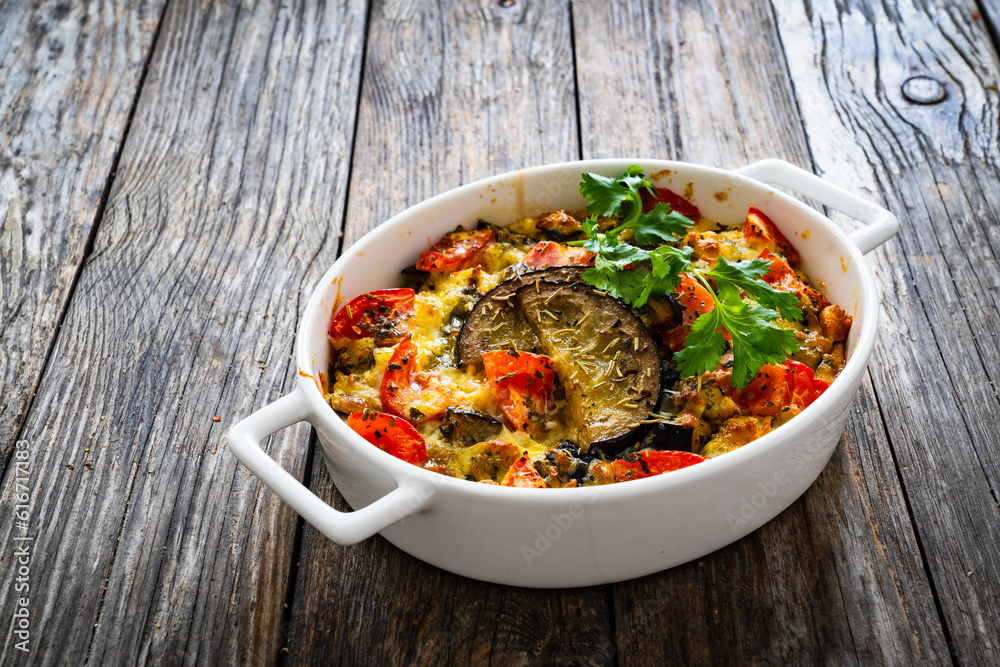 Bread casserole with mozzarella cheese, scrambled eggs, aubergine and tomatoes on wooden table
Bread casserole with mozzarella cheese, scrambled eggs, aubergine and tomatoes on wooden table