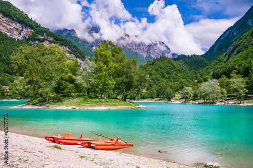 Amazing beautiful turquoise lake Tenno in Trentino region of Italy, surrouded by Alps mountains.  panoramic view with tiny island and canoe