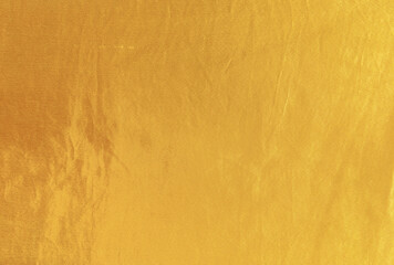 Gold silk texture background. Yellow shiny gold fabric sheet surface with light reflection, vibrant satin golden luxury wallpaper