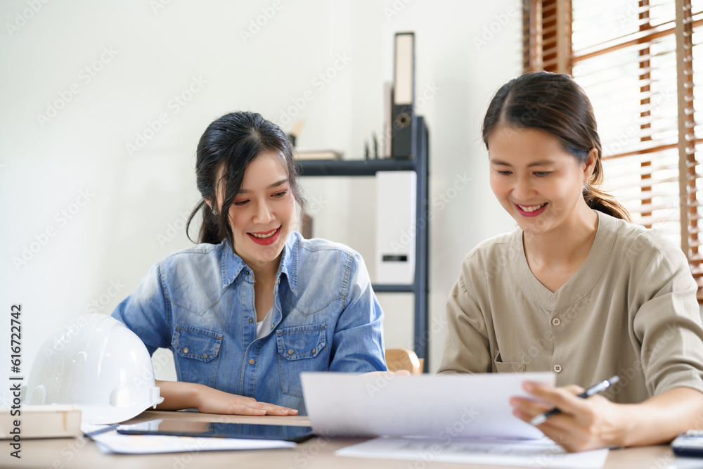 Engineering construction concept, Two female engineers is discussing construction and taking notes Engineering construction concept, Two female engineers is discussing construction and taking notes