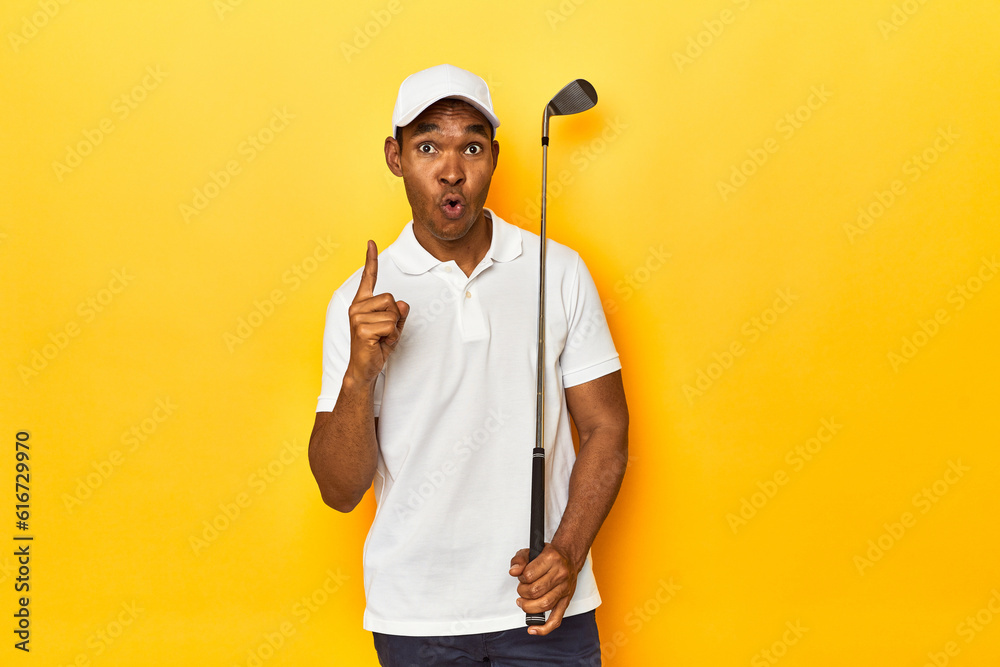 African American man golfer, yellow studio backdrop, having some great idea, concept of creativity.