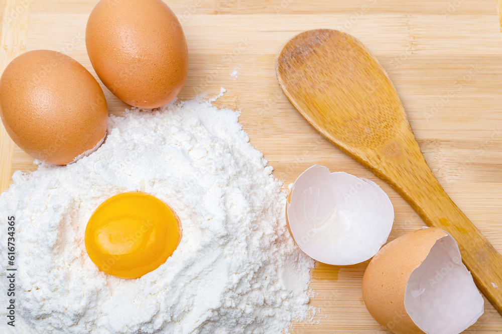 egg yolk, flour, two eggs and a wooden spoon egg yolk, flour, two eggs and a wooden spoon