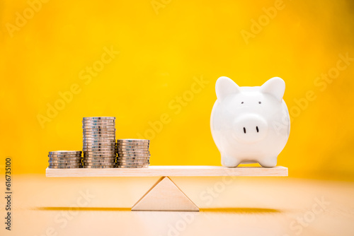 Piggy bank and gold coin with recommend an investment goal of the victory for ones success and home put on the scales on the yellow background in the office, Loan for investment in the future concept.