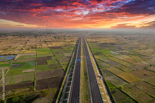 orbit aerial drone shot of new delhi mumbai jaipur express elevated highway showing six lane road with green feilds with rectangular farms