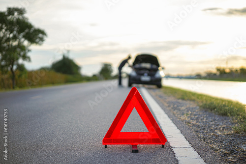 red emergency stop sign with broken down car on the road waiting to be repaired. Close-up of red emergency stop sign placed on the road for vehicle accidents or breakdowns for road safety.