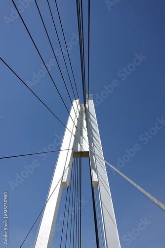 Modern urban cable-stayed bridge with metal ropes over cloudless blue sky © DyMaxFoto
