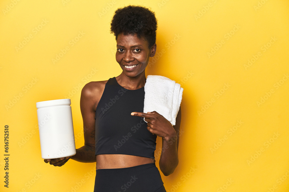 Obraz premium African woman in sportswear with protein powder and towel
