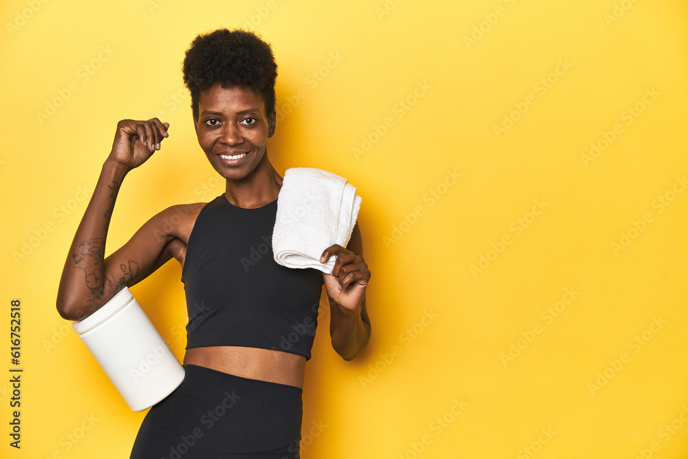 Fototapeta premium African woman in sportswear with protein powder and towel