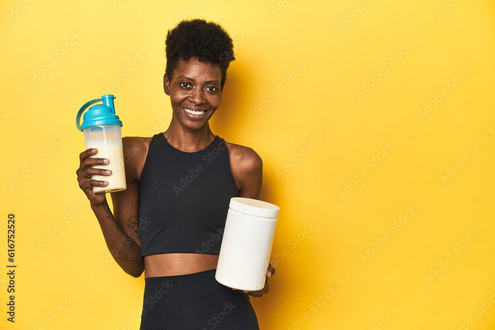 Naklejka premium African woman in sportswear with protein powder and shake.