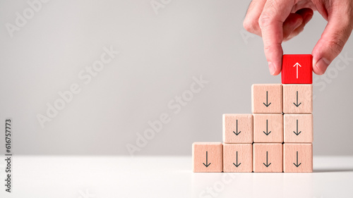 Hand placing wooden block cube reversing perspective direction arrow up opposite way thinking leadership on white table background. Mind changing sign symbol problem solving decision making concept.