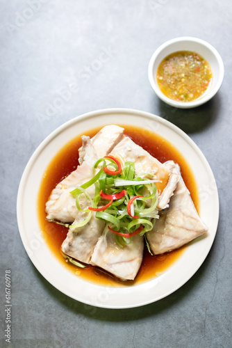 Sea bass fillet steam with soy sauce. Top view on black table background.