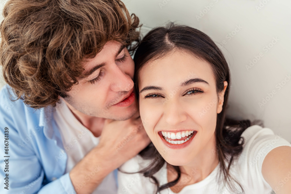 Happy smiling young couple taking selfie photo while resting at home Joyful young couple smiling and taking selfie photo while boyfriend kissing his girlfriend Woman and man enjoying date together Happy smiling young couple taking selfie photo while resting at home Joyful young couple smiling and taking selfie photo while boyfriend kissing his girlfriend Woman and man enjoying date together