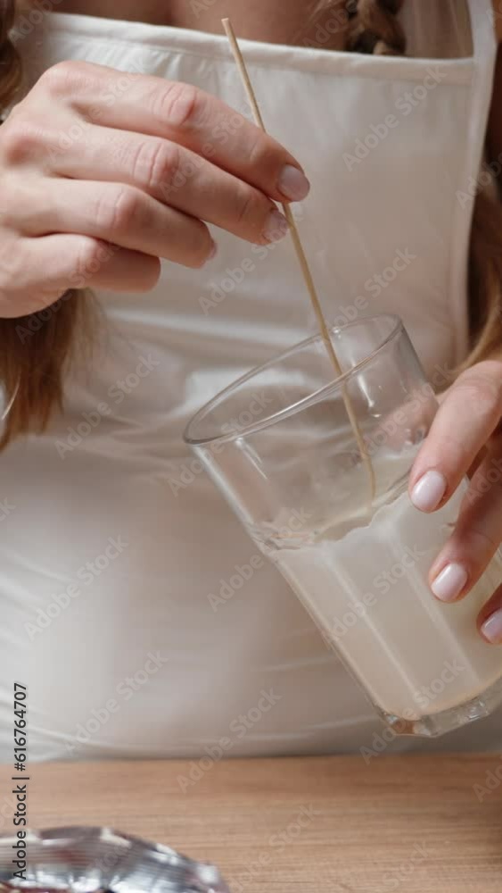 The woman dips the strawberry into white chocolate and gently shakes off the excess, in slow motion. Vertical video. The woman dips the strawberry into white chocolate and gently shakes off the excess, in slow motion. Vertical video.