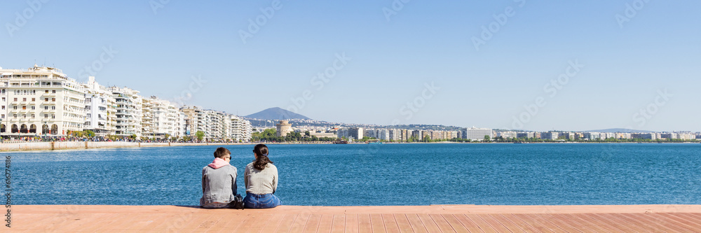 Young couple enjoying the view along the bay of the Aegean Sea with white tower Thessaloniki in Central Macedonia in Greece
