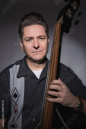 Vertical studio portrait of a 40 years old male musician playing the double bass rockabilly style