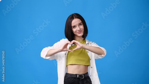 4k video of girl making heart shape with her hands on blue backround.