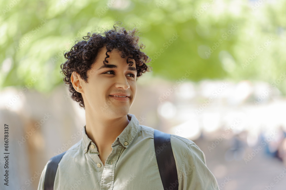 Smiling handsome hispanic student looking away outdoors Smiling handsome hispanic student looking away outdoors