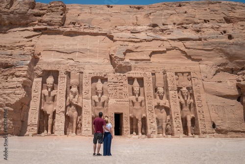 Young couple embraced, on their backs, enjoying the temple of Abu Simbel on her trip through Egypt. Temple of Queen Nefertari.
