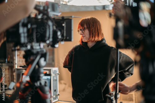 The director is a woman at work on the set. The director works with a group or with playback during the filming of a movie, commercial or TV series. Film crew, equipment and group. 