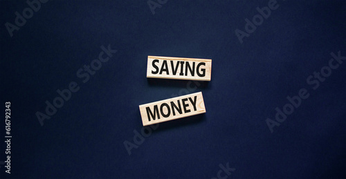 Saving money symbol. Concept words Saving money on wooden blocks on a beautiful black table black background. Business, support and saving money concept. Copy space.