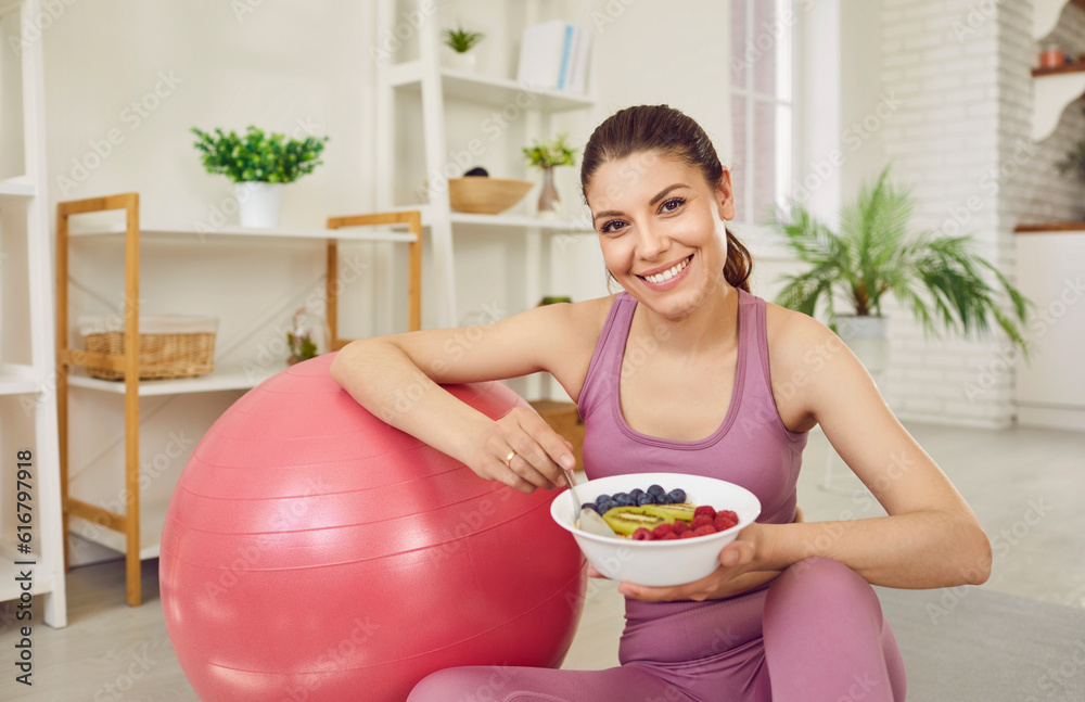 Φωτογραφία Portrait of a young sporty slim woman wearing sportswear eating healthy food after working out at home