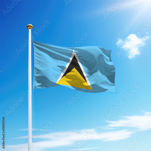 Waving flag of Saint Lucia on flagpole with sky background.