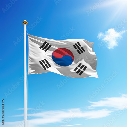 Waving flag of South Korea on flagpole with sky background.