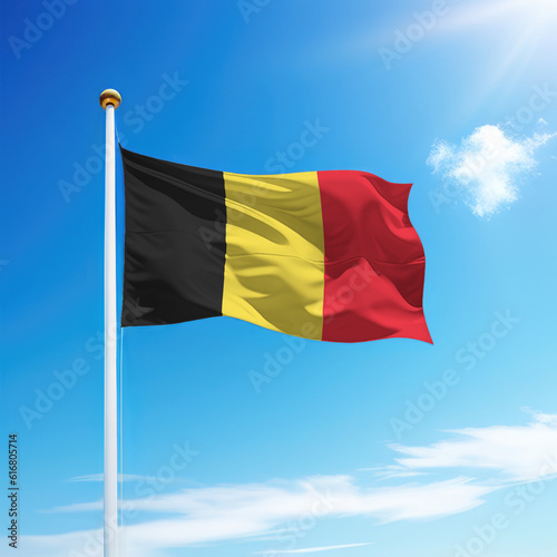 Waving flag of Belgium on flagpole with sky background.