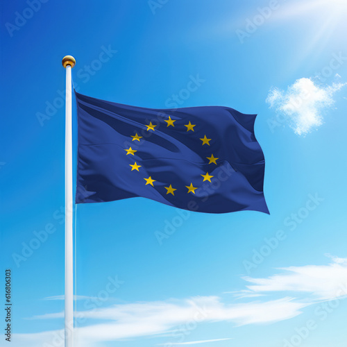 Waving flag of European Union on flagpole with sky background.