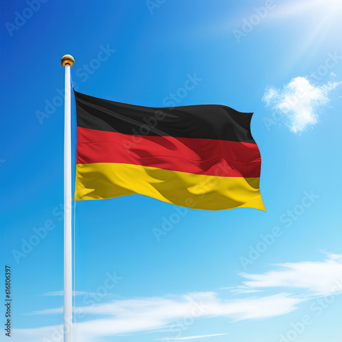 Waving flag of Germany on flagpole with sky background.