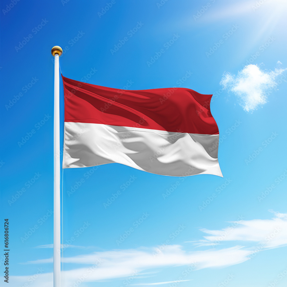 Waving flag of Monaco on flagpole with sky background.