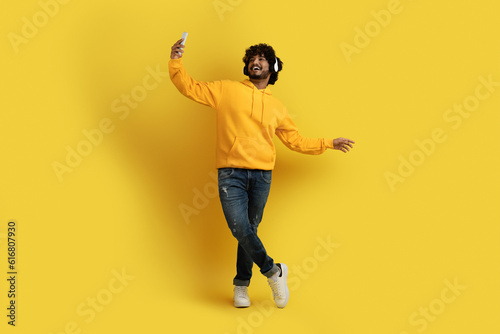 Cheerful indian guy taking selfie while listening to music