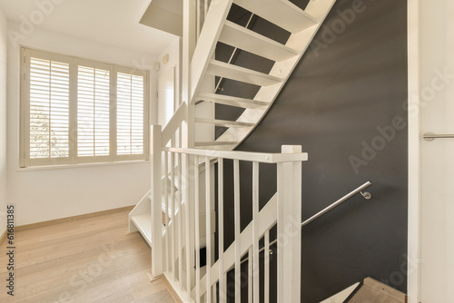 a staircase with white railings and wood flooring in a modern style home entryway to the stairs is painted black