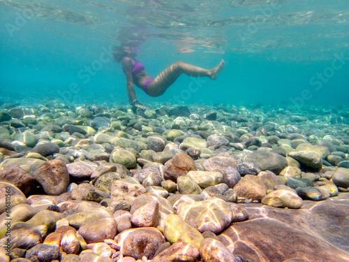 Giovane donna fa snorkeling nell'acqua cristallina dell'Isola delle Sirene a Taormina photo
