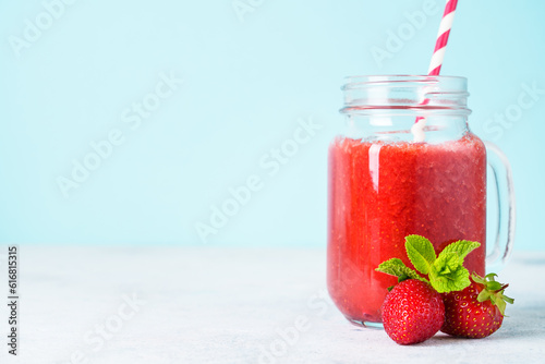 Strawberry smoothie with fresh berries at blue background.
