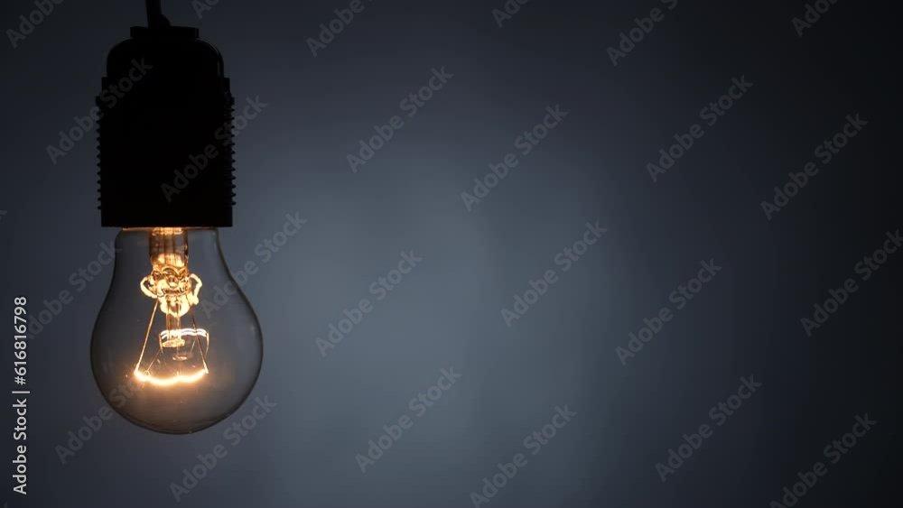 Tungsten spiral filament lamp flashes on a wire. Dolly shot. Close-up