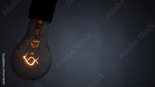 Tungsten spiral filament lamp swings on a wire. Slow motion