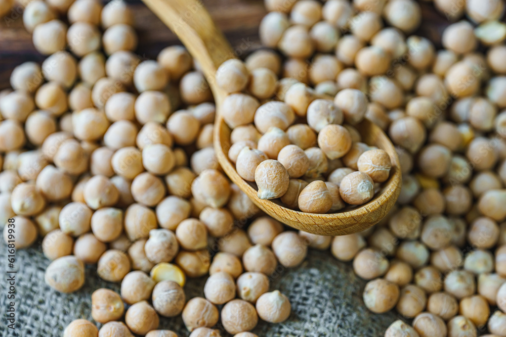 raw chickpeas in a wooden spoon on a rustic wooden cutting board close-up. raw chickpeas in a wooden spoon on a rustic wooden cutting board close-up.
