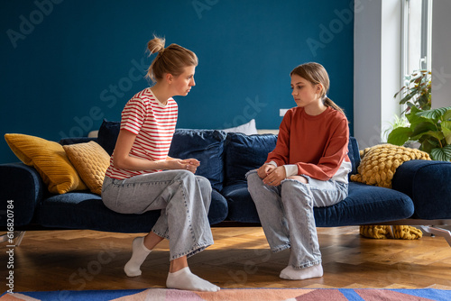 Difficult conversation between single mother and teenager at home. Important conflict adolescent topic between woman and daughter. Family misunderstanding. Upset teen girl listens to mom admonitions 
