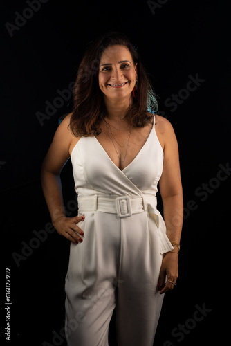 Studio portrait of beautiful mature woman, wearing white outfit, looking at camera.